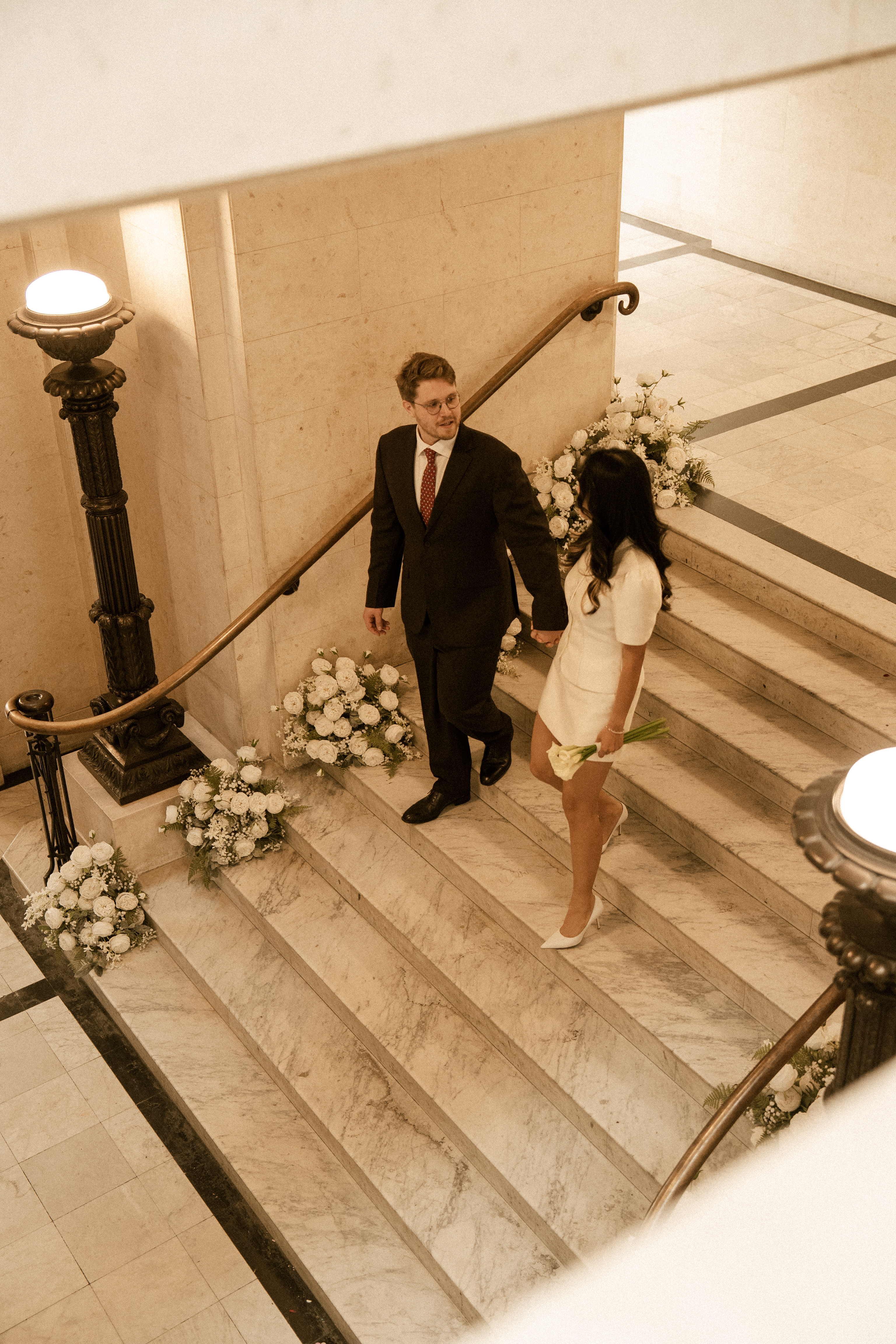 Anh and Mikhail holding hands on a flower-lined staircase